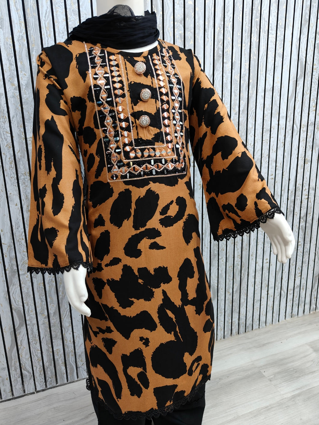 Leopard print dress with black accents on a mannequin against a striped background